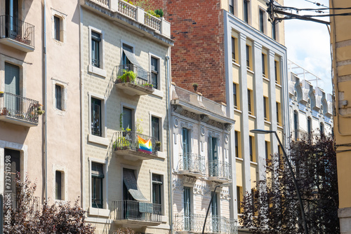Beautiful Spainish balcony with rainbow flag and much flowers in summer city.