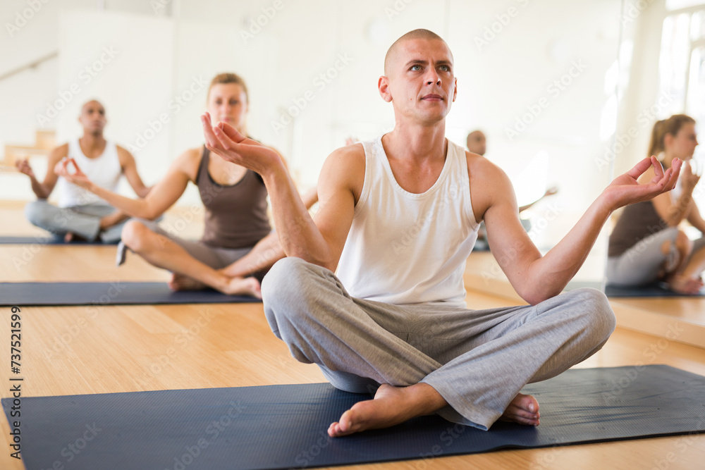 Portrait of man practicing yoga lesson at group class, maintaining healthy lifestyle