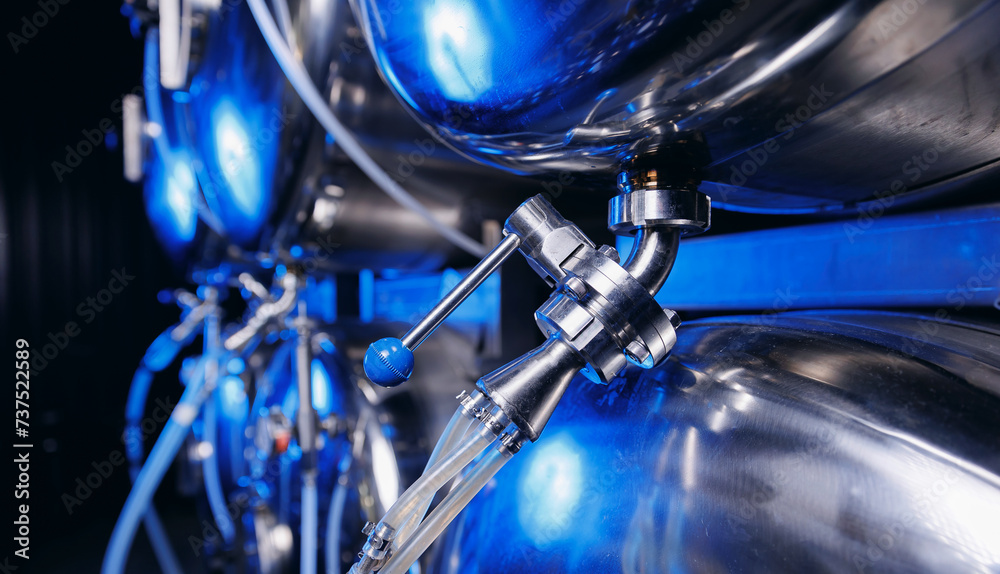 Obraz premium Industrial valve on factory beer drink and food equipment pipe stainless tubes with blue light