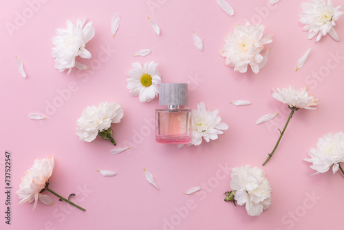 Perfume bottle spring aroma amidst white flowers on pink surface, Flat lay