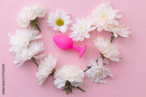 Concept erotic sex toy for female. Vacuum butt plug on pink background with flowers, flat lay