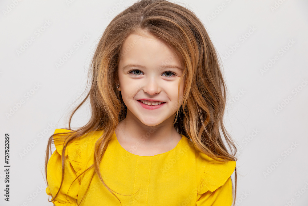 portrait of a happy little girl in a yellow dress on a white background. baby with a beautiful smile. Little Girl Woman Laughs, Looks at Camera. Copy space portrait of a happy little girl in a yellow dress on a white background. baby with a beautiful smile. Little Girl Woman Laughs, Looks at Camera. Copy space