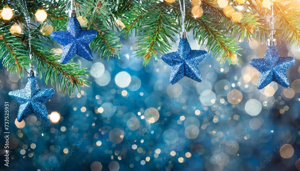 christmas tree with lights in blue stars hanging on fir branches with glittering and bokeh in abstract defocused background