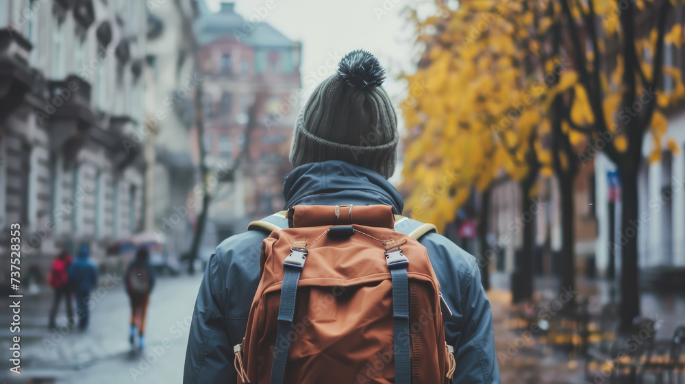 A solitary traveler with a backpack explores a rain-kissed city street lined with autumn trees.