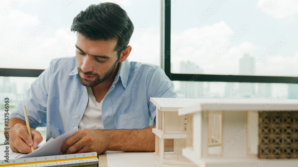 Portrait of caucasian architect engineer designs real estate on blueprint. Professional engineer drawing blueprint while looking at house model construction. Civil engineering concept. Tracery