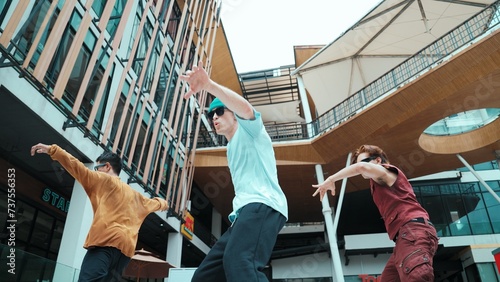 Caucasian group practice break dancing together. Energetic street dancer team in stylish fashion outfit perform hip-hop footstep at mall or city. Low angle view. Outdoor sport 2024. Endeavor.