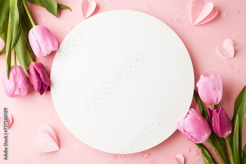 Blank canvas of spring: blooms and wishes. Top view flat lay of pink tulips and paper hearts on a pastel pink background with blank circle for heartfelt spring messages #737566589