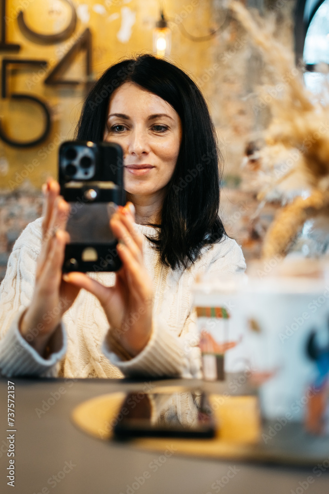 A young beautiful woman takes a selfie in a cafe. A young beautiful woman takes a selfie in a cafe.