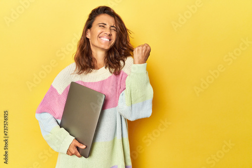 Middle-aged woman using laptop on yellow