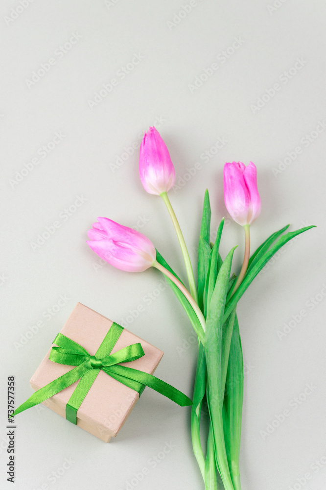 Gift box and bouquet of pink tulips on light green background. Women's day, Mother's day, spring concept. Top view, flat lay