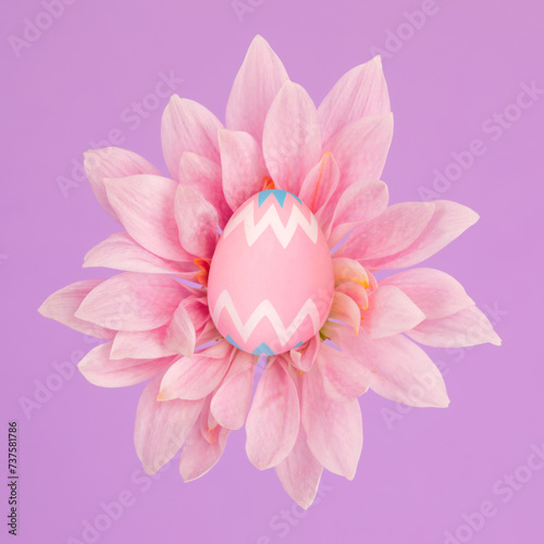 Tiny pink decorated Easter egg sitting in blooming flower with blank center copy space for greeting.