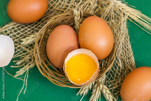 Jajka w koszyku. Rozbite jajko widoczne żółtko i całe jaja. 