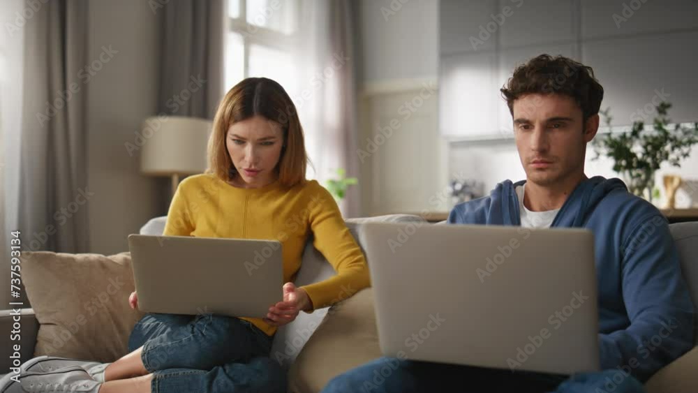 Focused spouses texting laptops sitting sofa together home closeup. Remote work Focused spouses texting laptops sitting sofa together home closeup. Remote work
