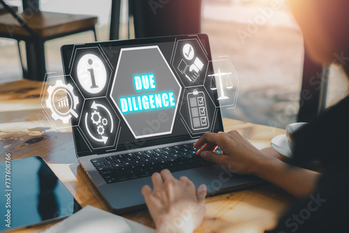 Due diligence concept, Business woman using laptop computer on desk with due diligence icon on cirtual screen.