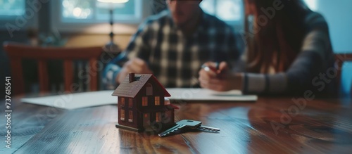 Young couple with key and tiny toy house on table for deal buying a new property. AI generated image photo