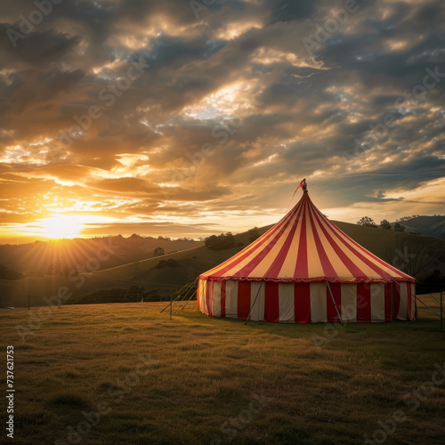 A whimsical circus tent set against a backdrop of rolling hills and a setting sun 
