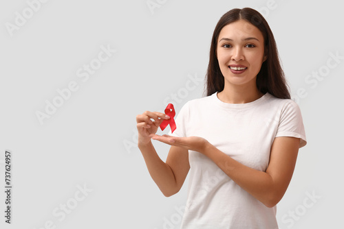 Pretty young woman with red ribbon on white background. World AIDS Day concept © Pixel-Shot
