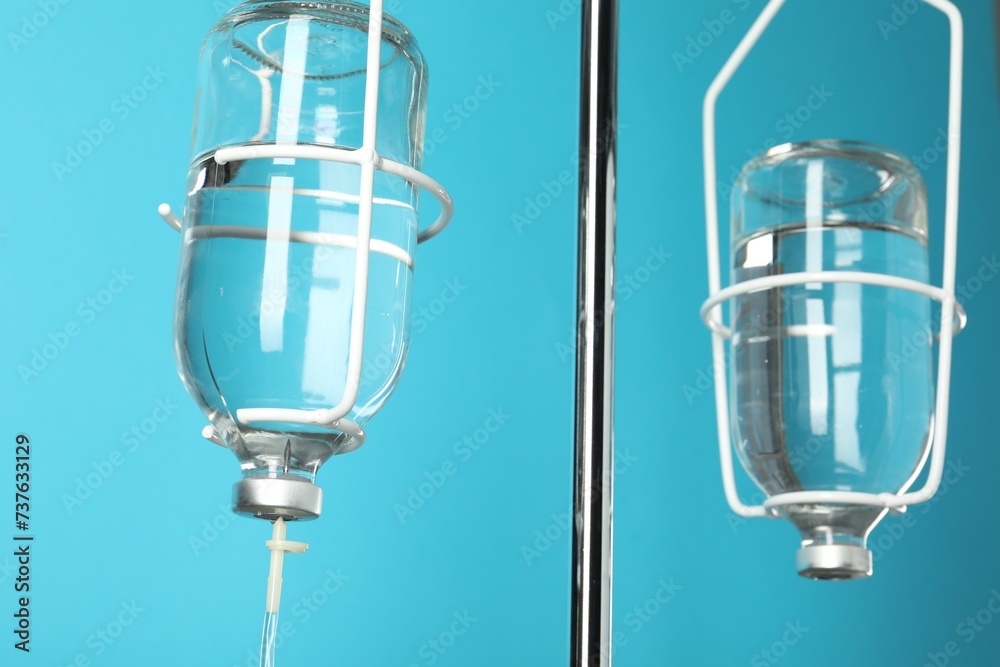 IV infusion set on pole against light blue background, closeup