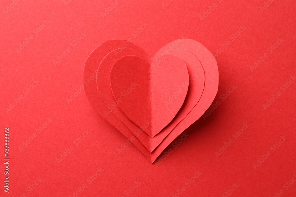 Paper hearts on red background, top view