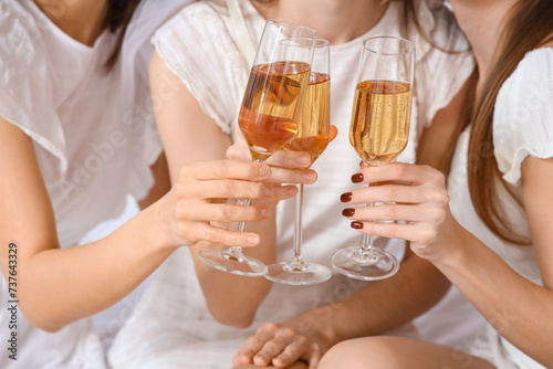 Young woman and her bridesmaids with champagne at Hen Party in bedroom, closeup