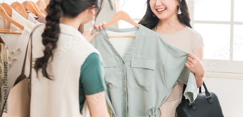 アパレルショップで洋服を買い物・ショッピングする女性とショップ店員
 photo