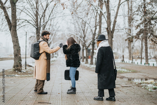 Young business coworkers engage in a conversation outdoors on a snowy winter day.
