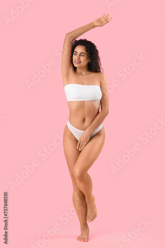 Beautiful young happy African-American woman with stretch marks on her body against pink background