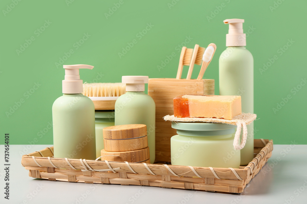 Composition with soap, tooth brushes and jars of cream on table near green wall. Different bath supplies Composition with soap, tooth brushes and jars of cream on table near green wall. Different bath supplies