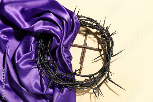 Crown of thorns with purple fabric and nails on beige background photo