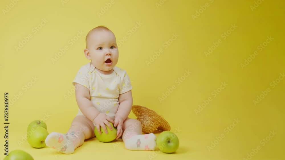 Cute baby girl with green apples sitting in studio on yellow background. Cute baby girl with green apples sitting in studio on yellow background.