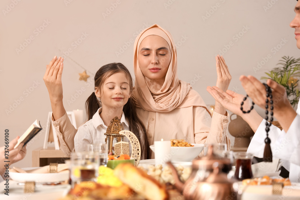 Happy Muslim mother with her little daughter praying before dinner at home. Ramadan celebration Happy Muslim mother with her little daughter praying before dinner at home. Ramadan celebration