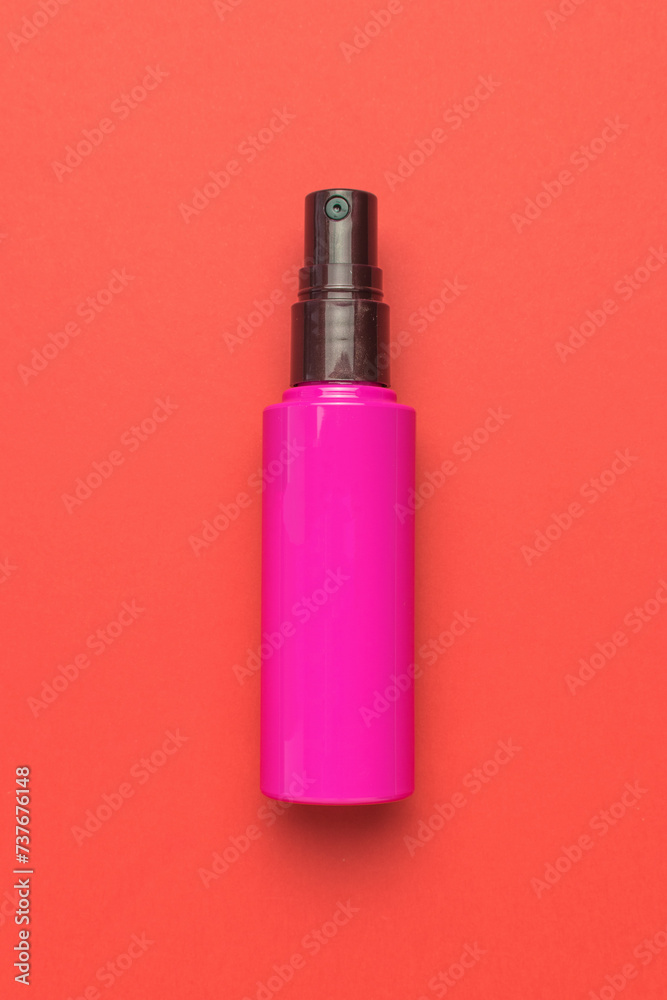 A red bottle with spray on a red background. A red bottle with spray on a red background.