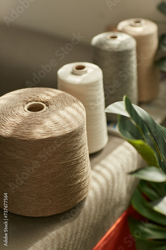 Brown and gray textile linen threads, coils intertwined, illuminated by sunlight indoors