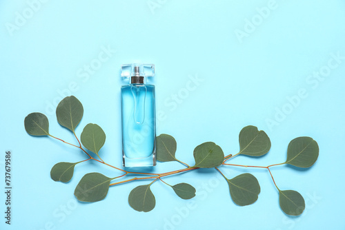 Bottle of perfume with leaves on blue background. Top view © Pixel-Shot