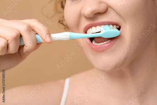 Beautiful young happy woman brushing teeth on brown background  closeup