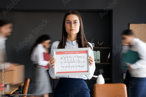 Fotografi Young business woman with evacuation plan in office