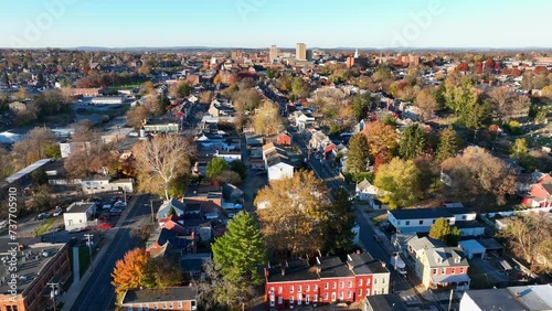 Small city in USA during autumn. Aerial orbit shot of suburb with colorful rowhouses and trees. Downtown city skyline view during sunset. photo