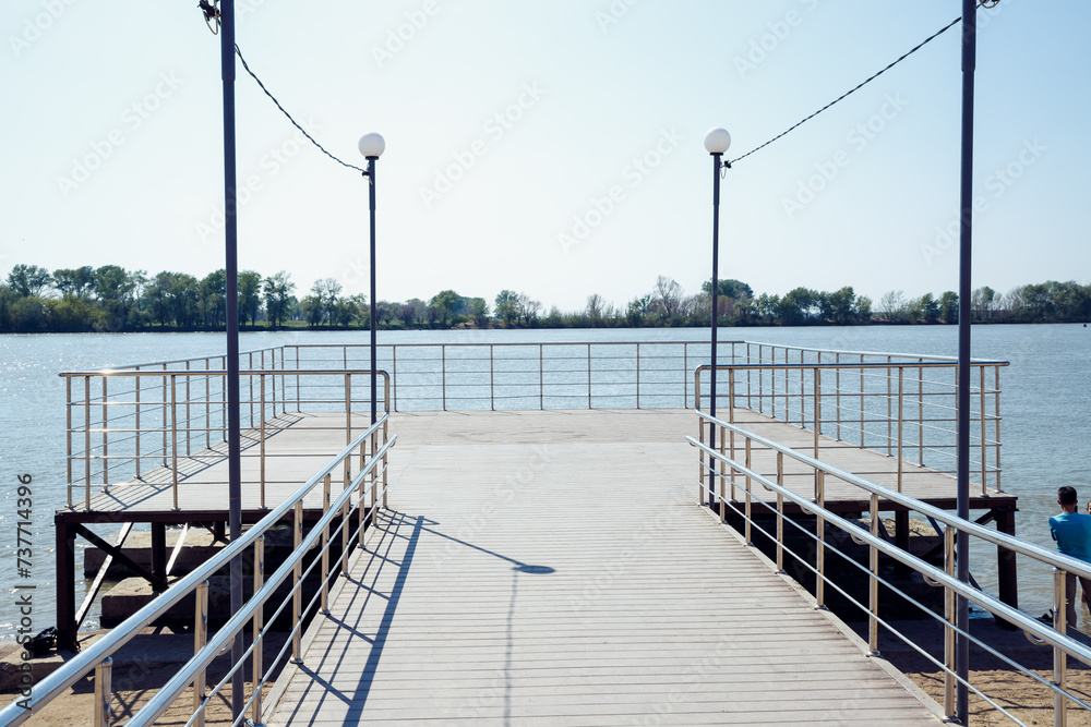 Obraz premium pleasure observation pier, Modern pier on public city beach of lake without people on sunny day