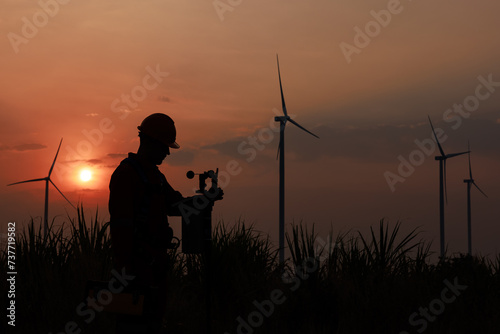 Silhouette of young men engineer standing checking equipment wind turbine beside agricultural sugarcane and wind turbine morning sunlight