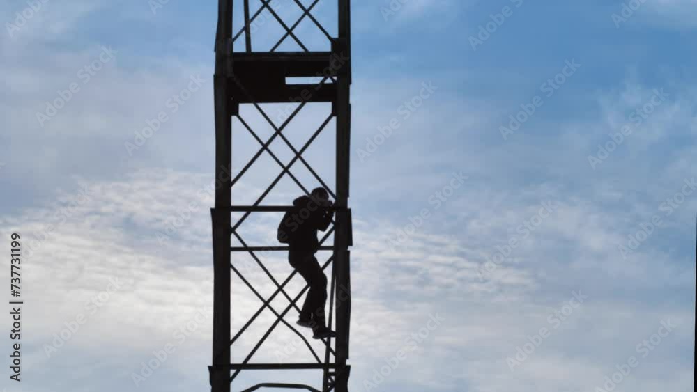 Silhouette of a male antenna tower maintenance technician doing
