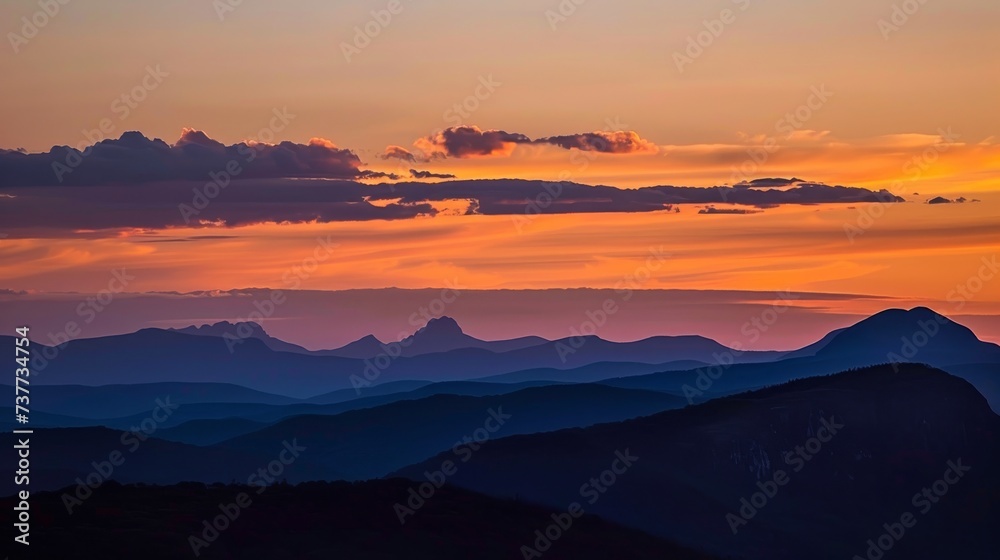 Fototapeta premium Silhouettes of majestic peaks under a sky ablaze with sunset colors
