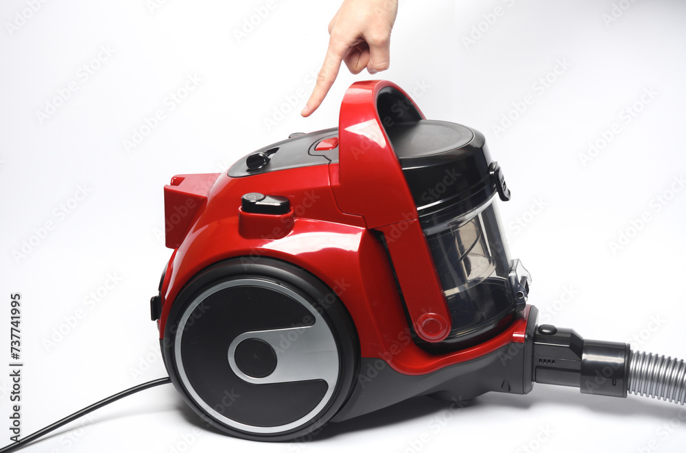 Fototapeta premium Finger presses the button of a red vacuum cleaner
