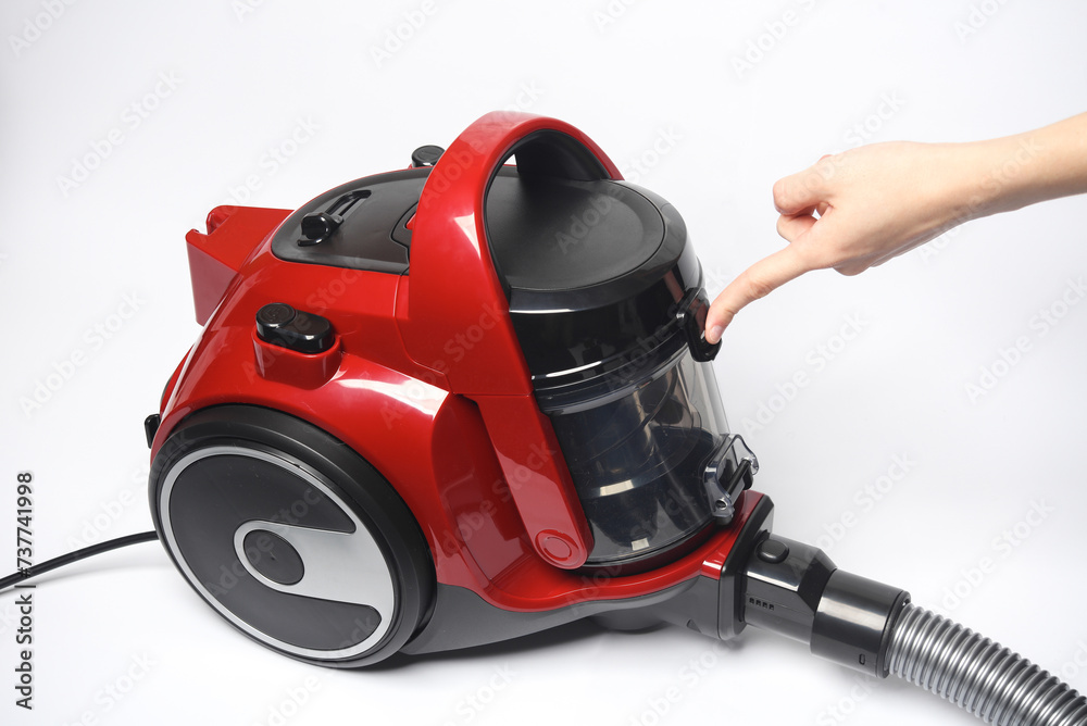 Finger presses the button of a red vacuum cleaner Finger presses the button of a red vacuum cleaner