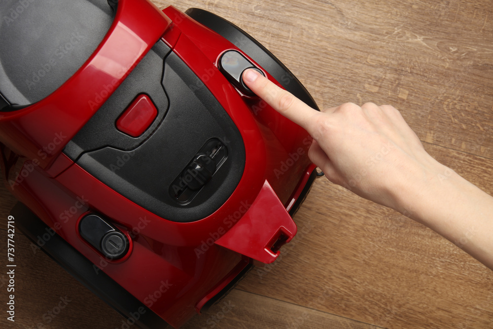 Fototapeta premium Finger presses the button of a red vacuum cleaner