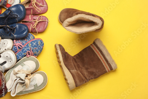 Many different children's shoes on yellow background. Top view