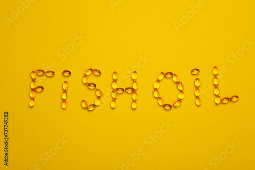 Fish oil word from capsules on yellow background photo