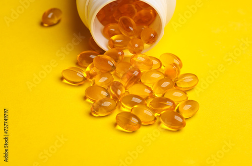 Fish oil capsules in a plastic jar on yellow background.