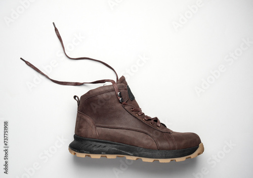Brown leather boot with untied laces on a white background