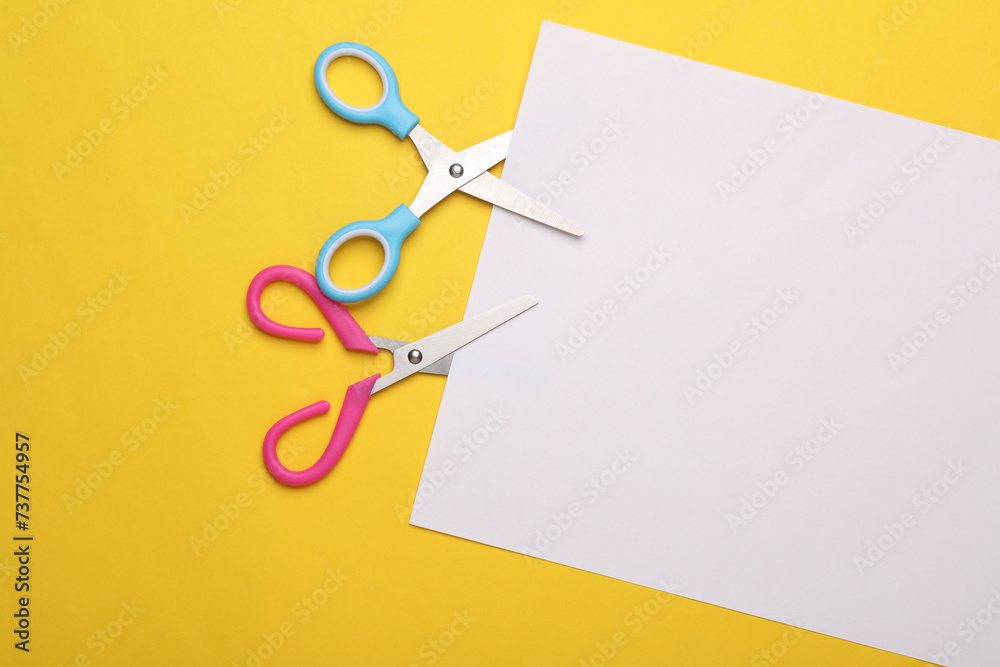 Scissors for creativity cut a white sheet of paper on a yellow background Scissors for creativity cut a white sheet of paper on a yellow background