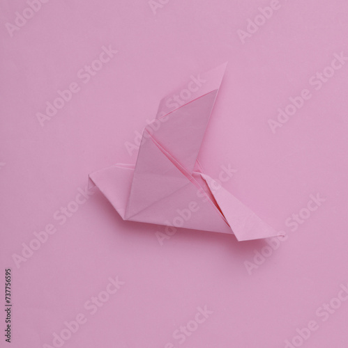 Pink origami dove on a pink background. Peace symbol, no war